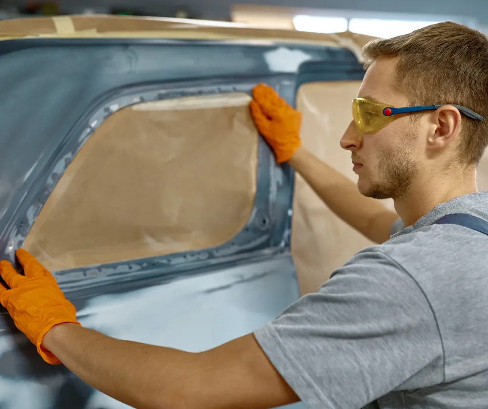 Technician prepping and masking a surface before painting