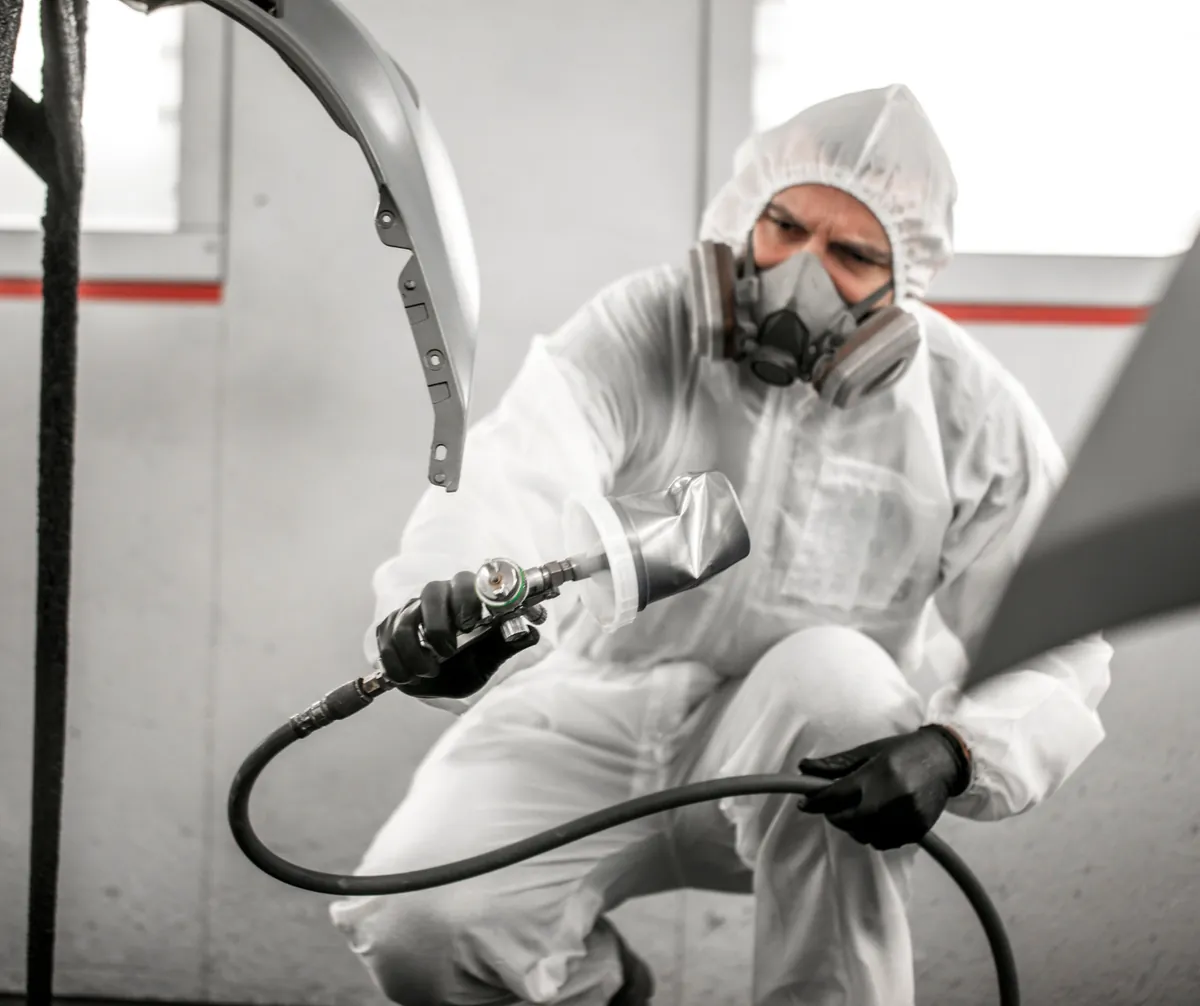 Technician holding a body panel during a parts replacement
